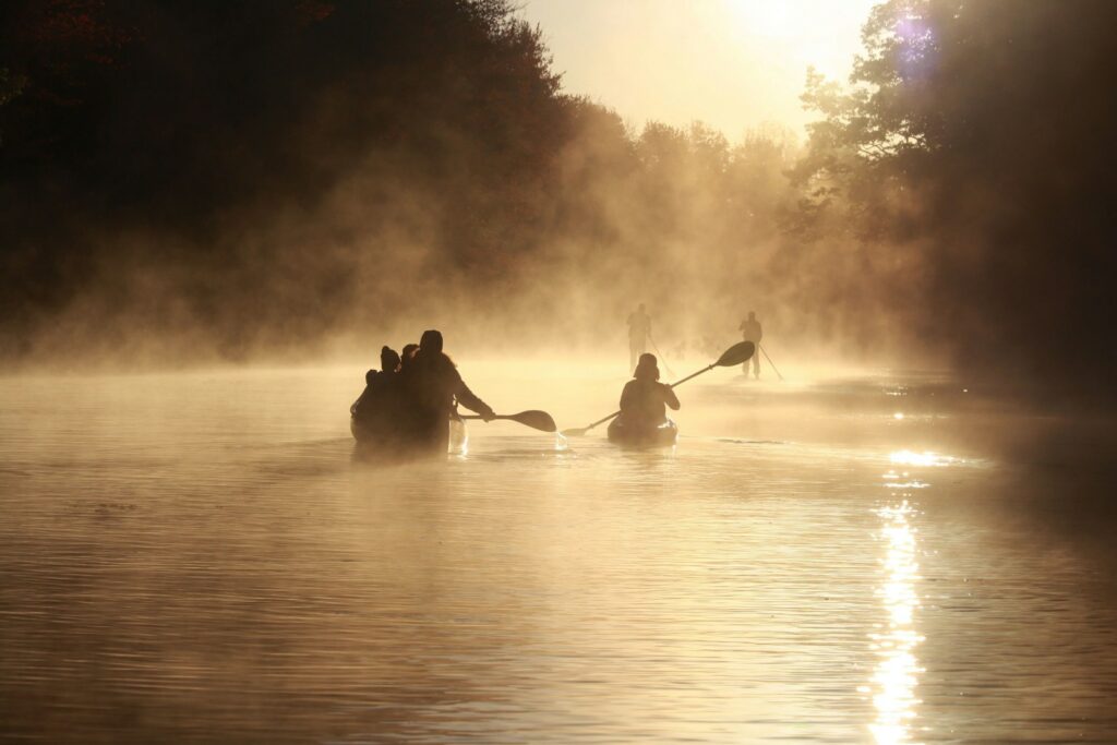 A group of people paddling on canoes on a lake.