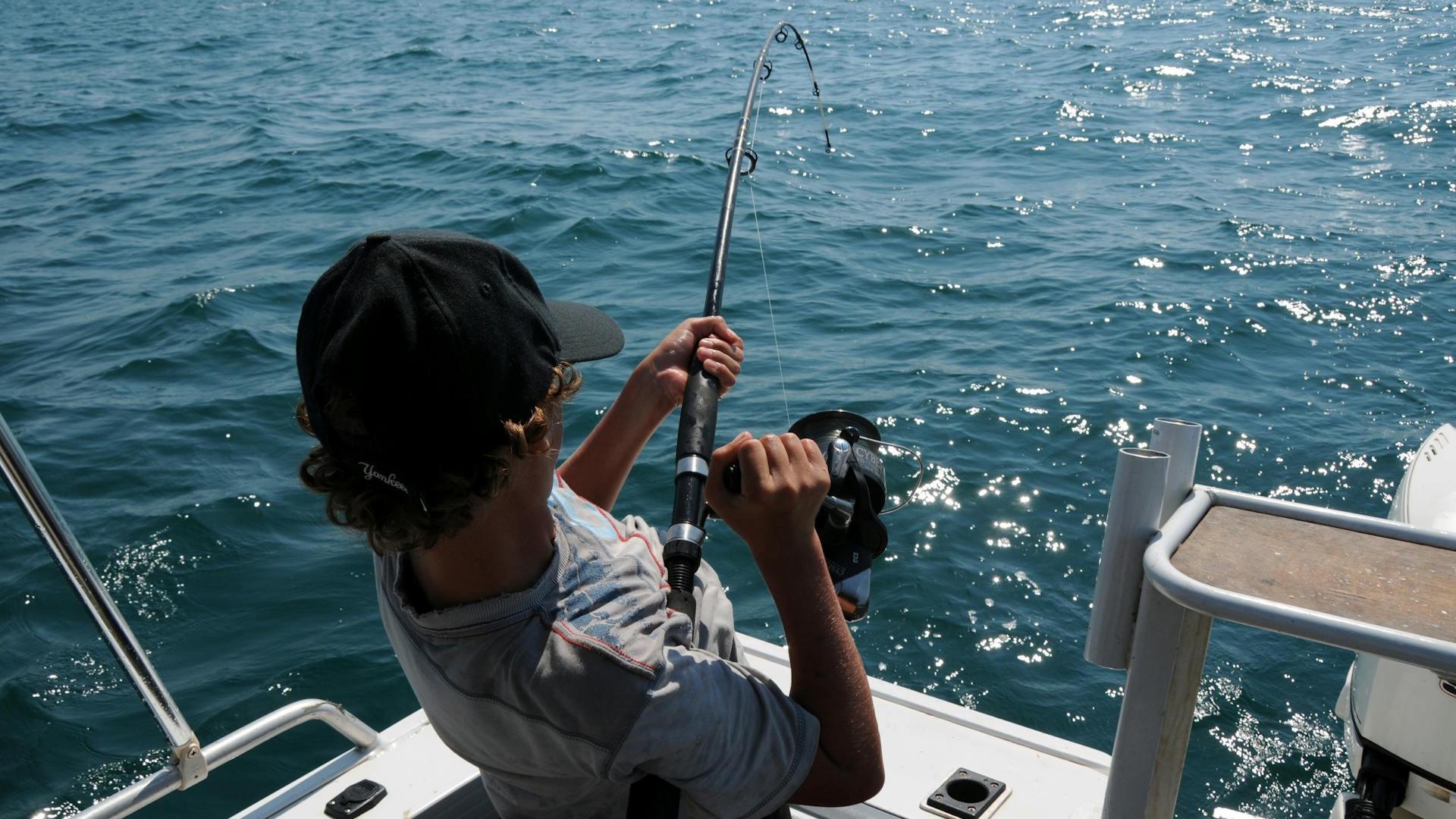 A young man actively fishing in the ocean near Broome, WA, enjoying a sunny day.