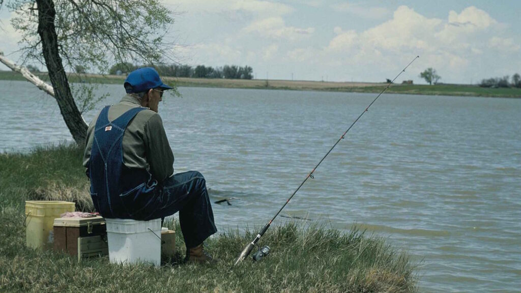 Old man fishing patiently by the water