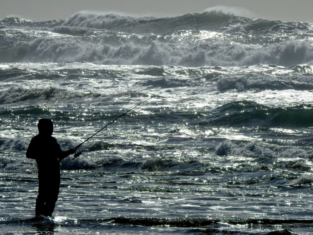A man fishing on sea waves during daytime.