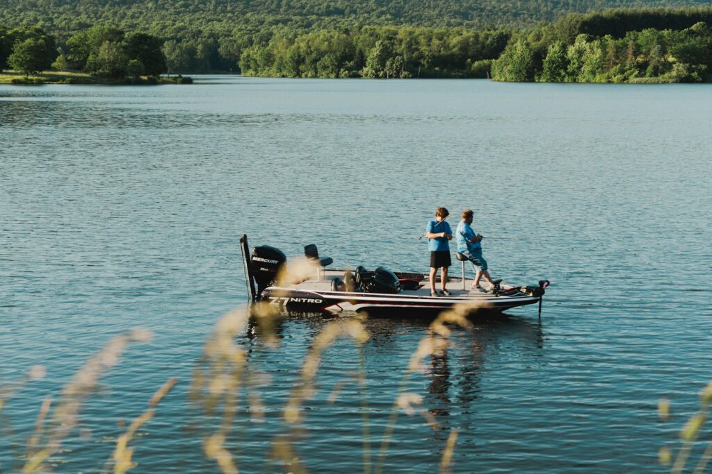 A group of people standing on top of a boat on a lake.