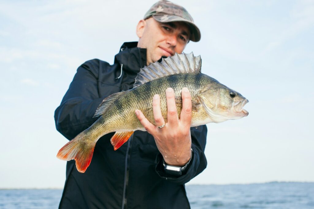 Man holding grey fish with ocean background.