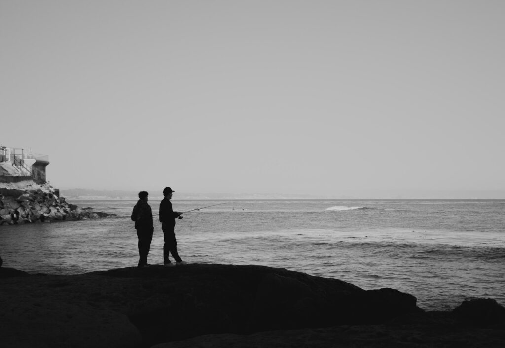 A couple of men standing on top of a beach next to the ocean.