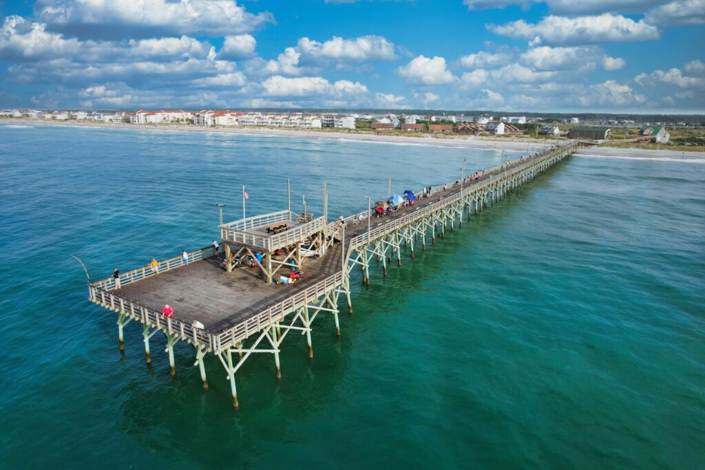 A pier by the ocean with people standing on it.