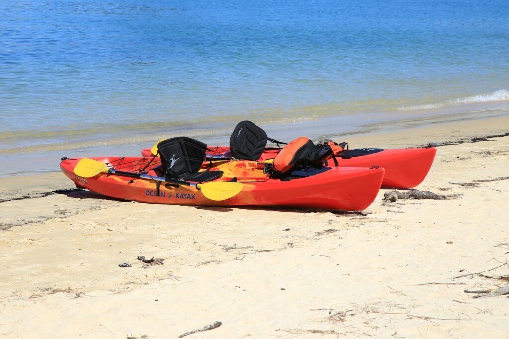 Red kayak on white sand beach during the day.