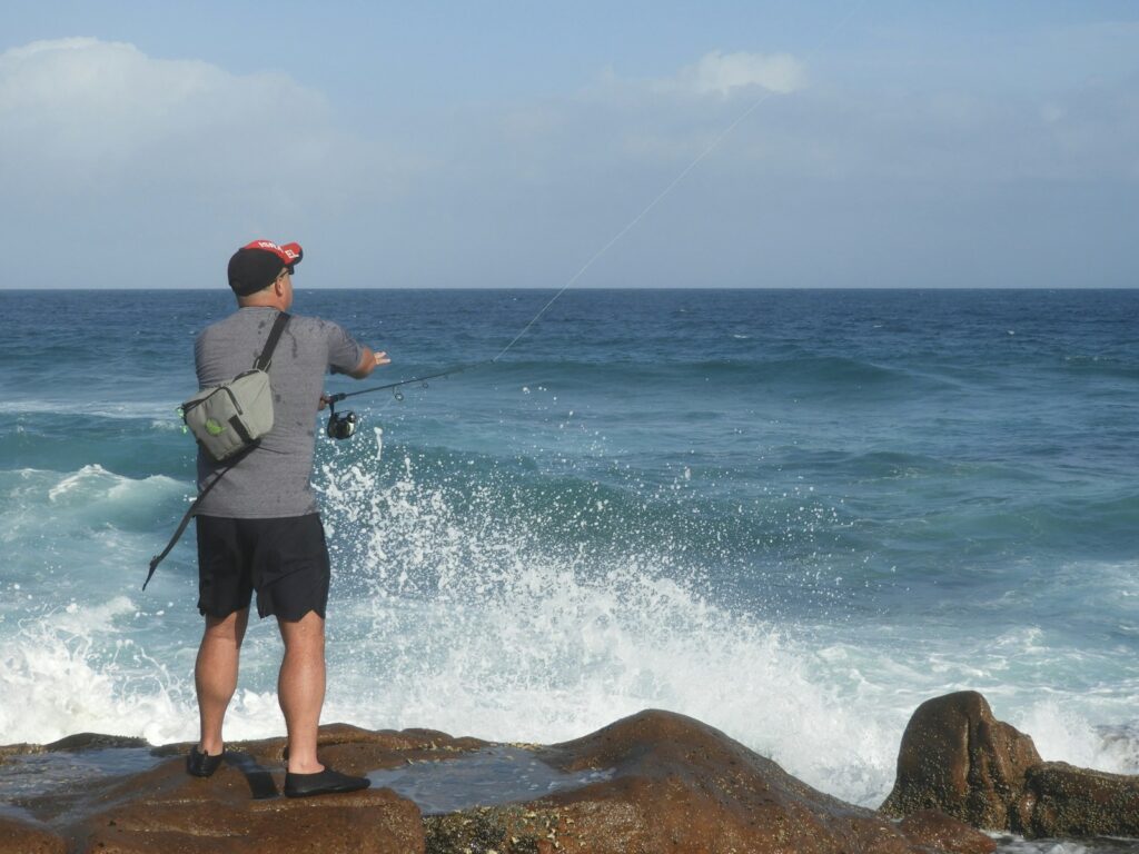 A man standing on top of a rock next to the ocean.