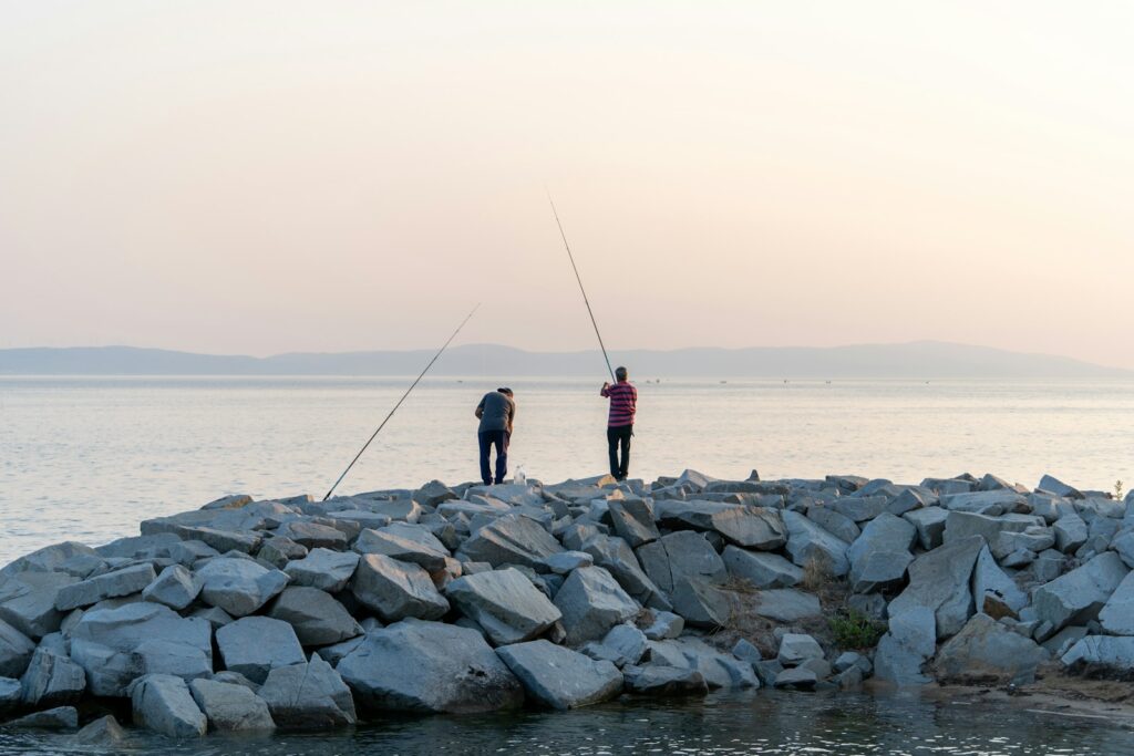 A couple of men standing on top of a pile of rocks.