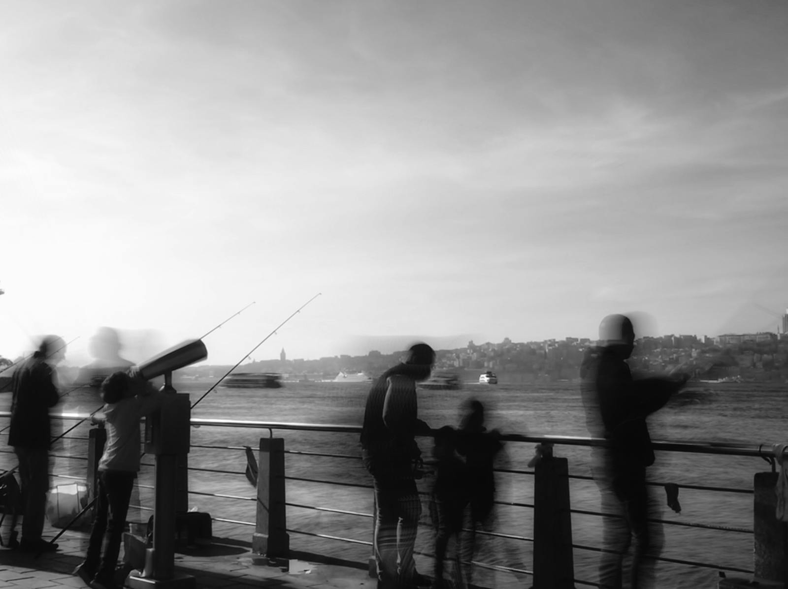 Silhouetted figures fishing by the waterfront, framed against a serene sunset backdrop.