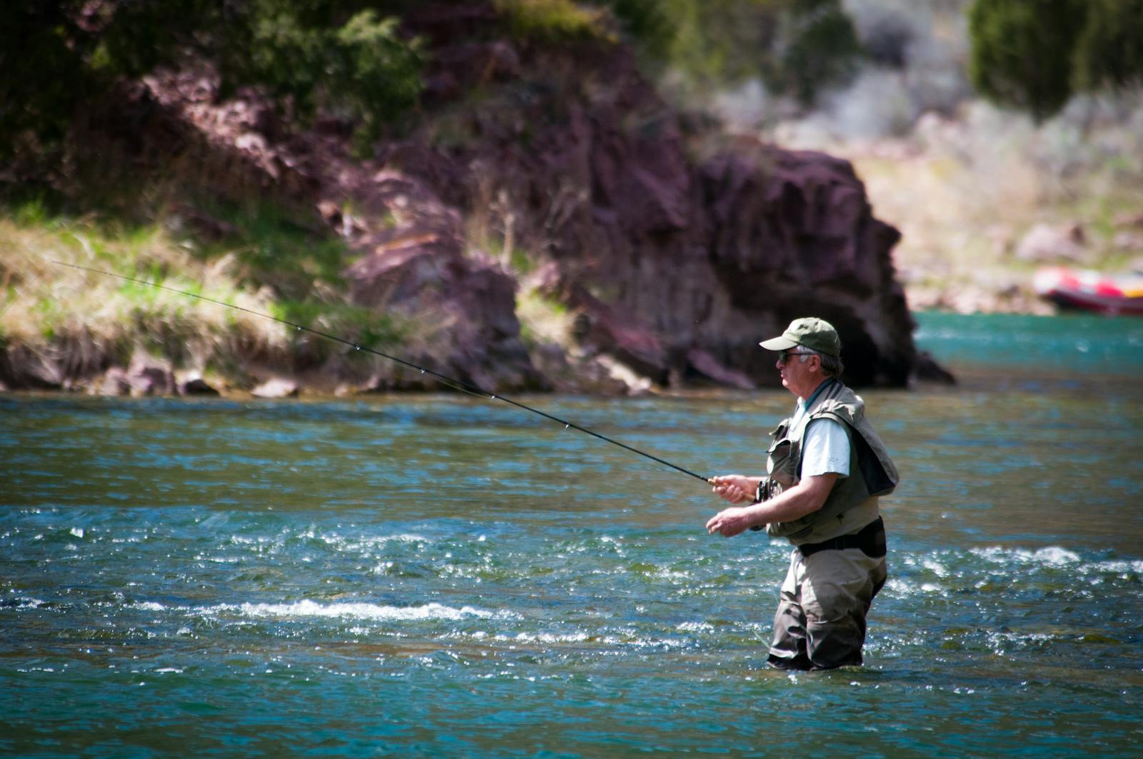 An adult man fly fishing in a tranquil river, surrounded by nature and beautiful scenery.