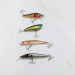 Variety of fishing lures arranged on a white surface for equipment showcase.