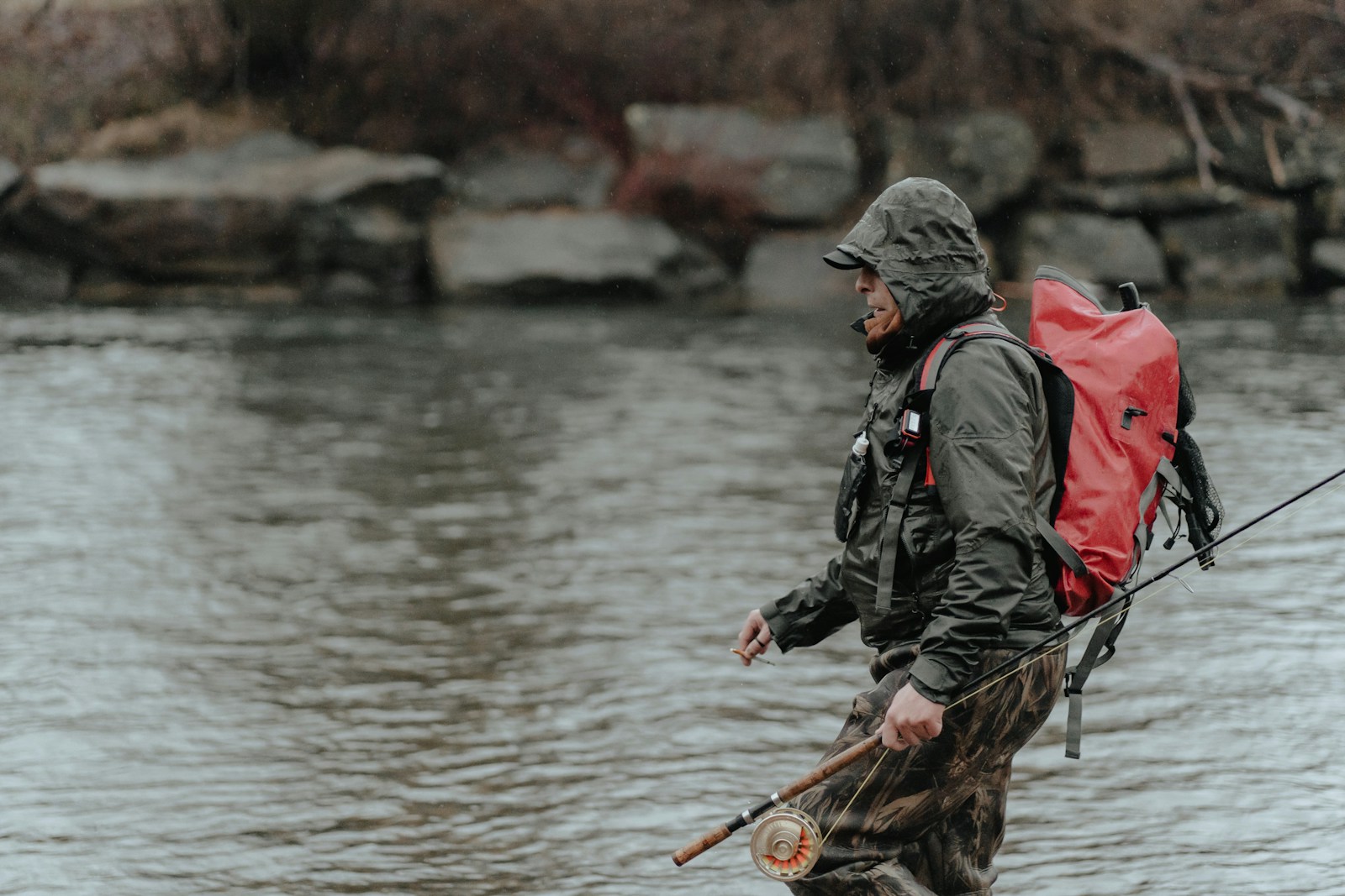 A man with a red backpack and a fishing pole.