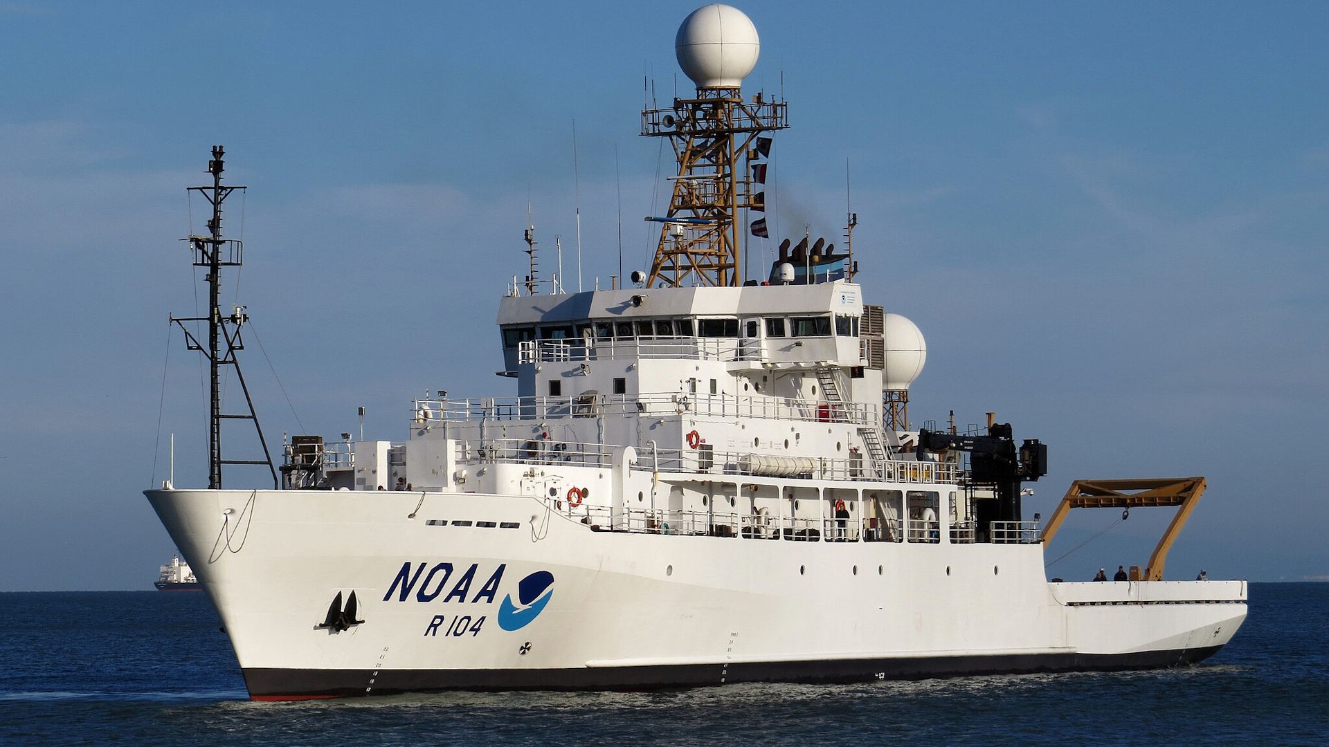 A large NOAA research vessel named "Ronald H. Brown" (R 104) sails through open waters under a clear sky.