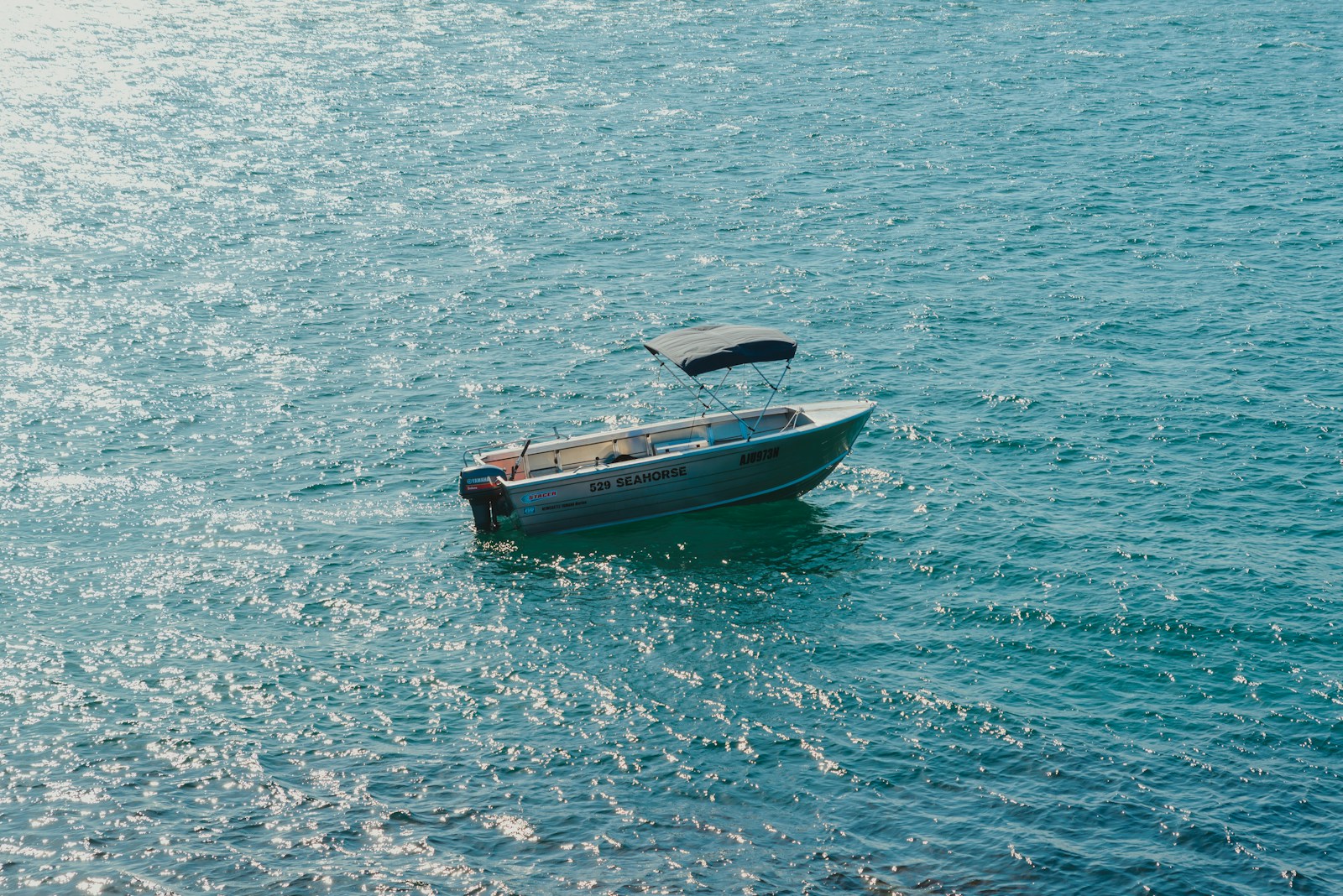 A small blue boat in the middle of the ocean.