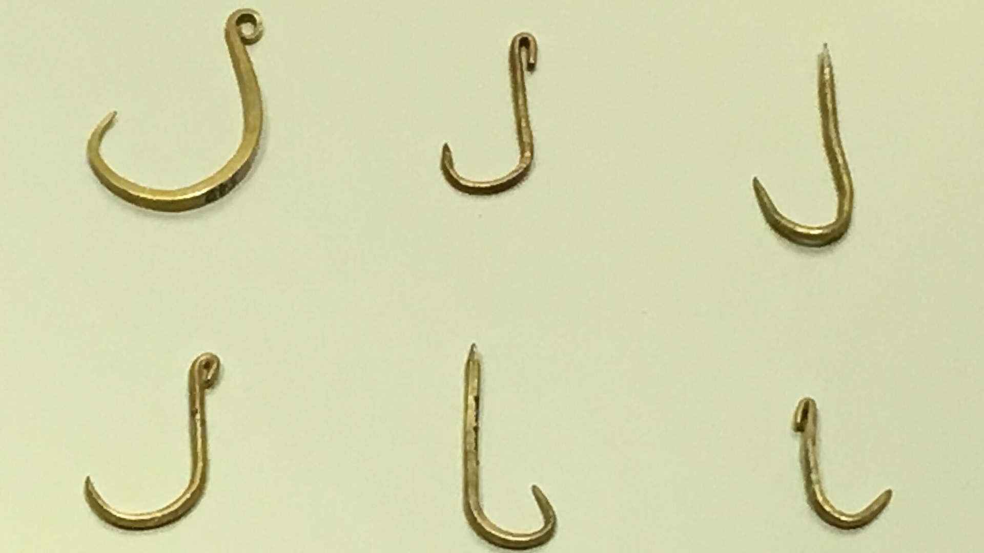 A collection of six different fishing hooks displayed on a light background, showcasing various shapes and sizes.