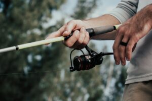 Person holding brown and black fishing rod.